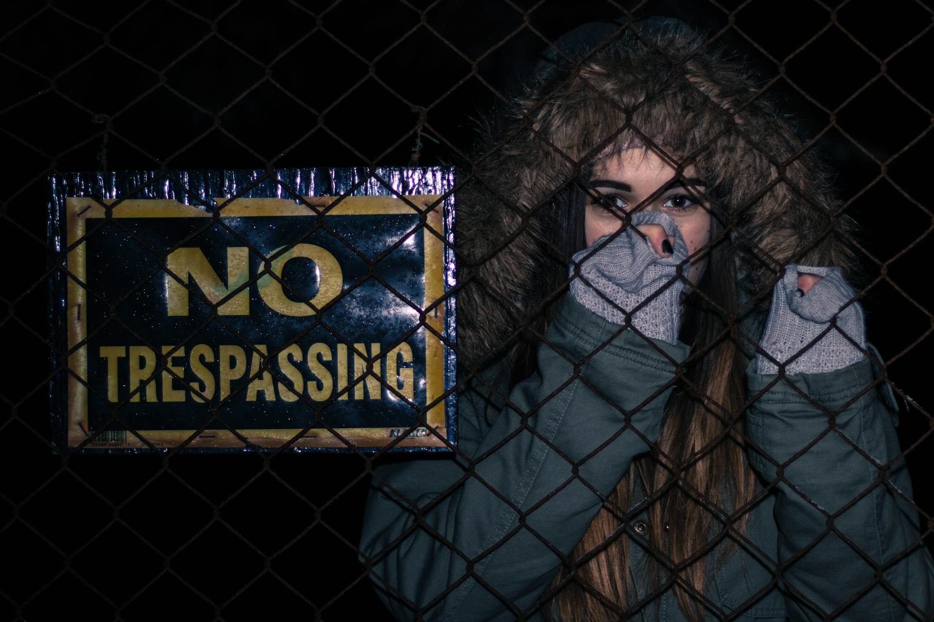 Woman Behind Black Chainlink Fence With No Trespassing Signage