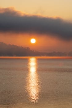 Beautiful sunrise reflecting over a peaceful lake with orange and pink hues in the sky.
