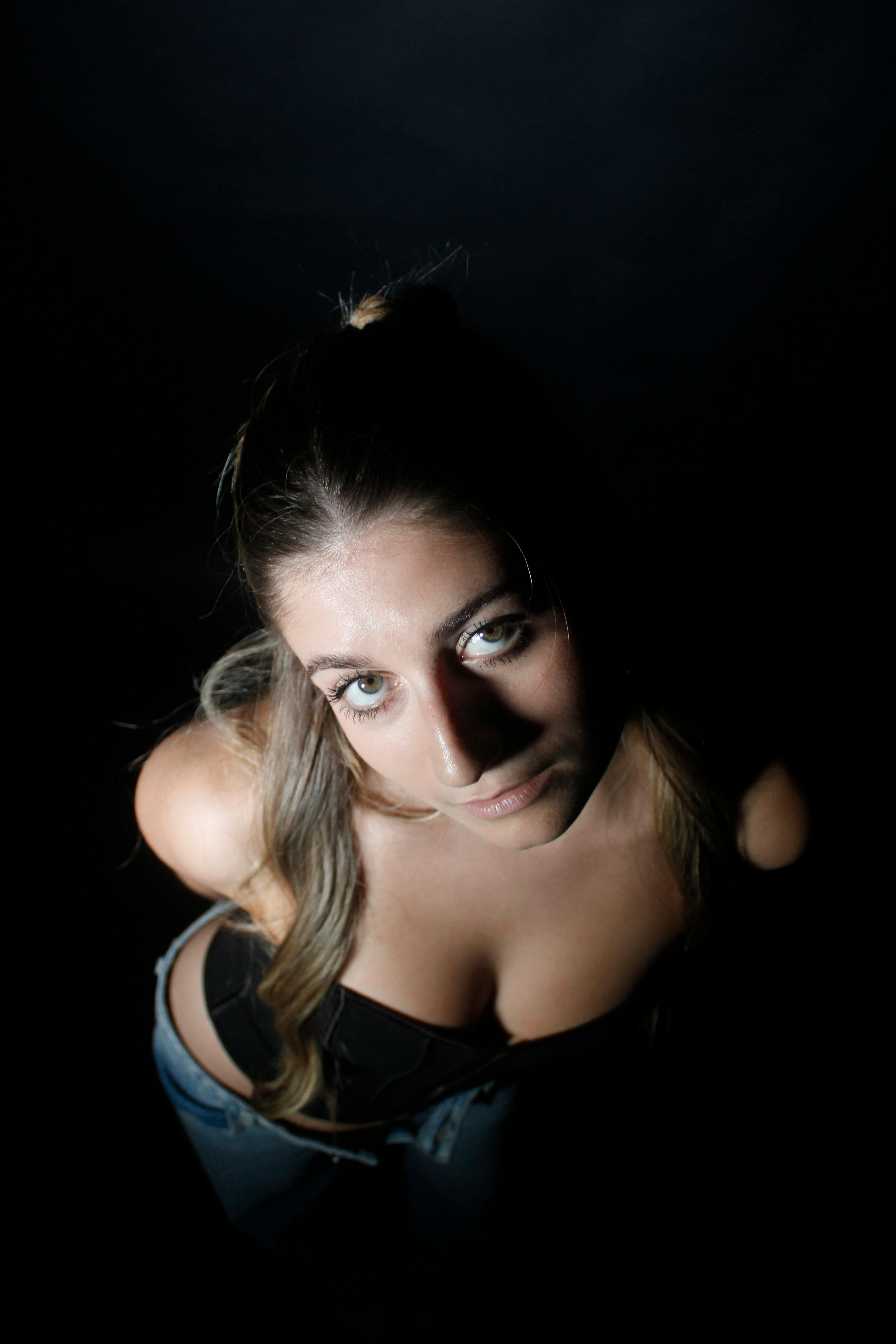 Gratis Potret seorang wanita yang menatap ke atas dengan pencahayaan dramatis dan suasana hati yang murung. Foto Stok