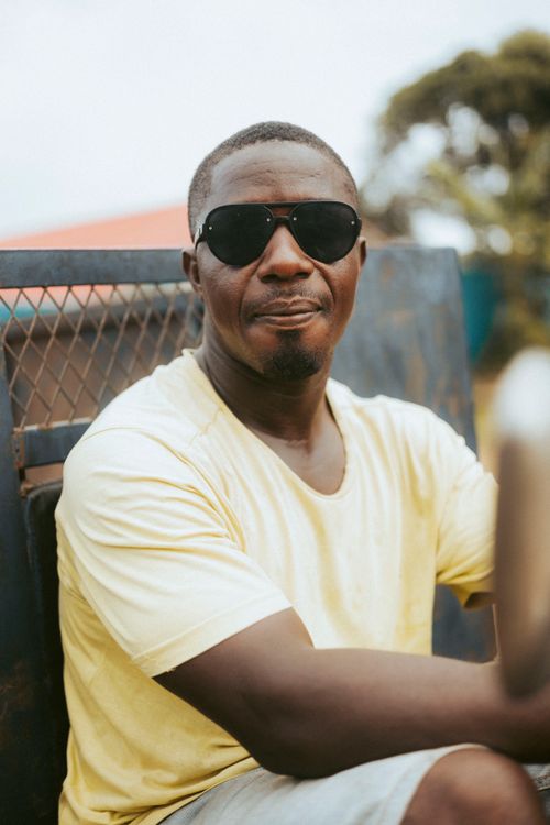 Free Casual portrait of a man wearing sunglasses and a yellow shirt outdoors in Monrovia, Liberia. Stock Photo
