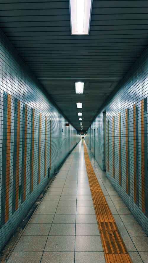 Free A brightly lit underground passageway with geometric tiled walls leads into the distance. Stock Photo