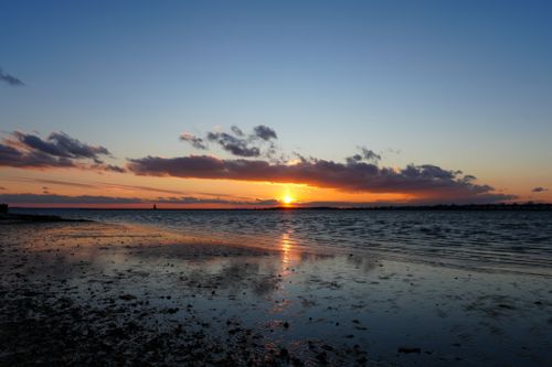 Free Beautiful sunset at the beach with vibrant colors reflecting on the water. Stock Photo