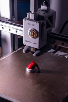 3D printer crafting a small Santa hat ornament, showcasing holiday-themed technology.
