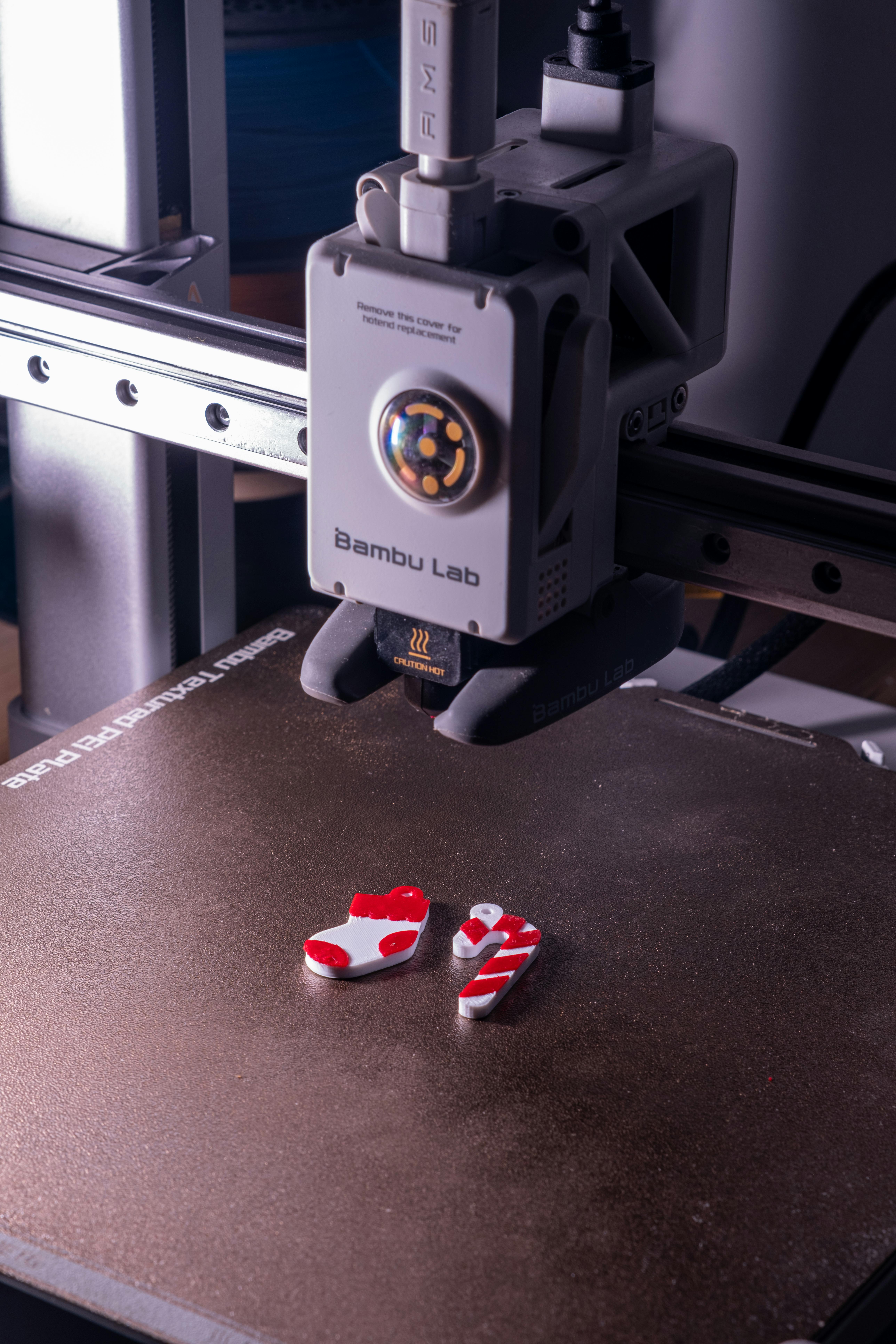 Close-up of a 3D printer creating red and white plastic objects.