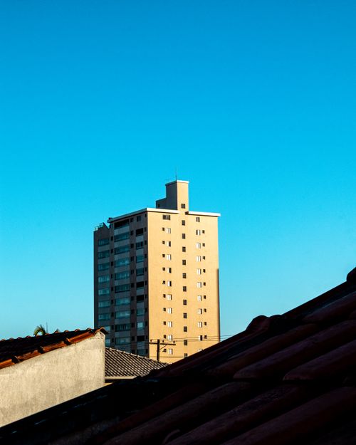 Free Cityscape featuring a high-rise building against a clear blue sky, capturing urban architecture. Stock Photo