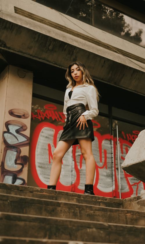 Free Stylish woman posing confidently on urban steps with graffiti background. Stock Photo