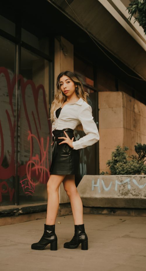 Free Stylish woman posing outdoors in urban setting with graffiti backdrop, wearing trendy outfit. Stock Photo