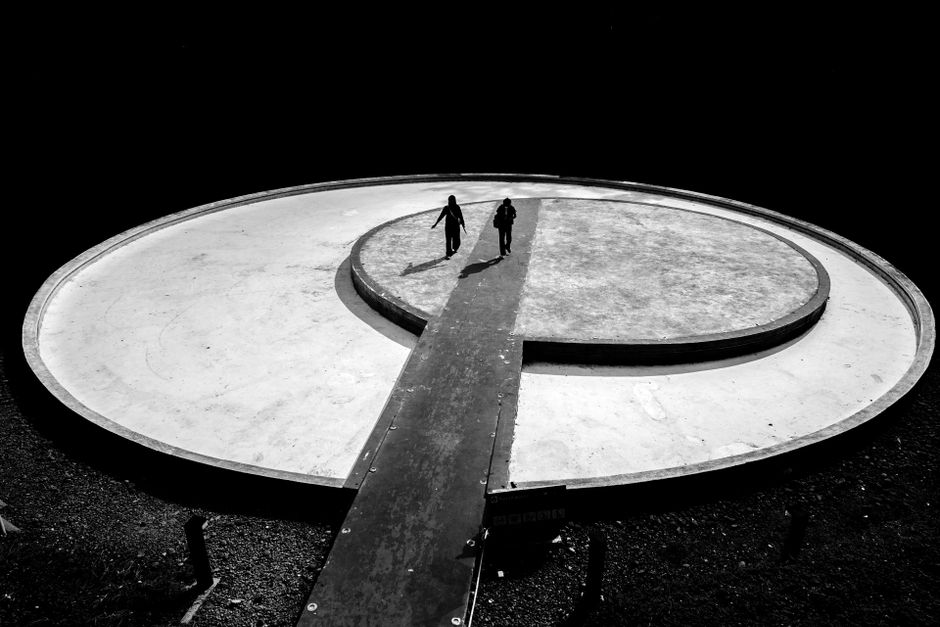 Black and white photo featuring two silhouettes on a circular structure, perfect for minimalist design themes.