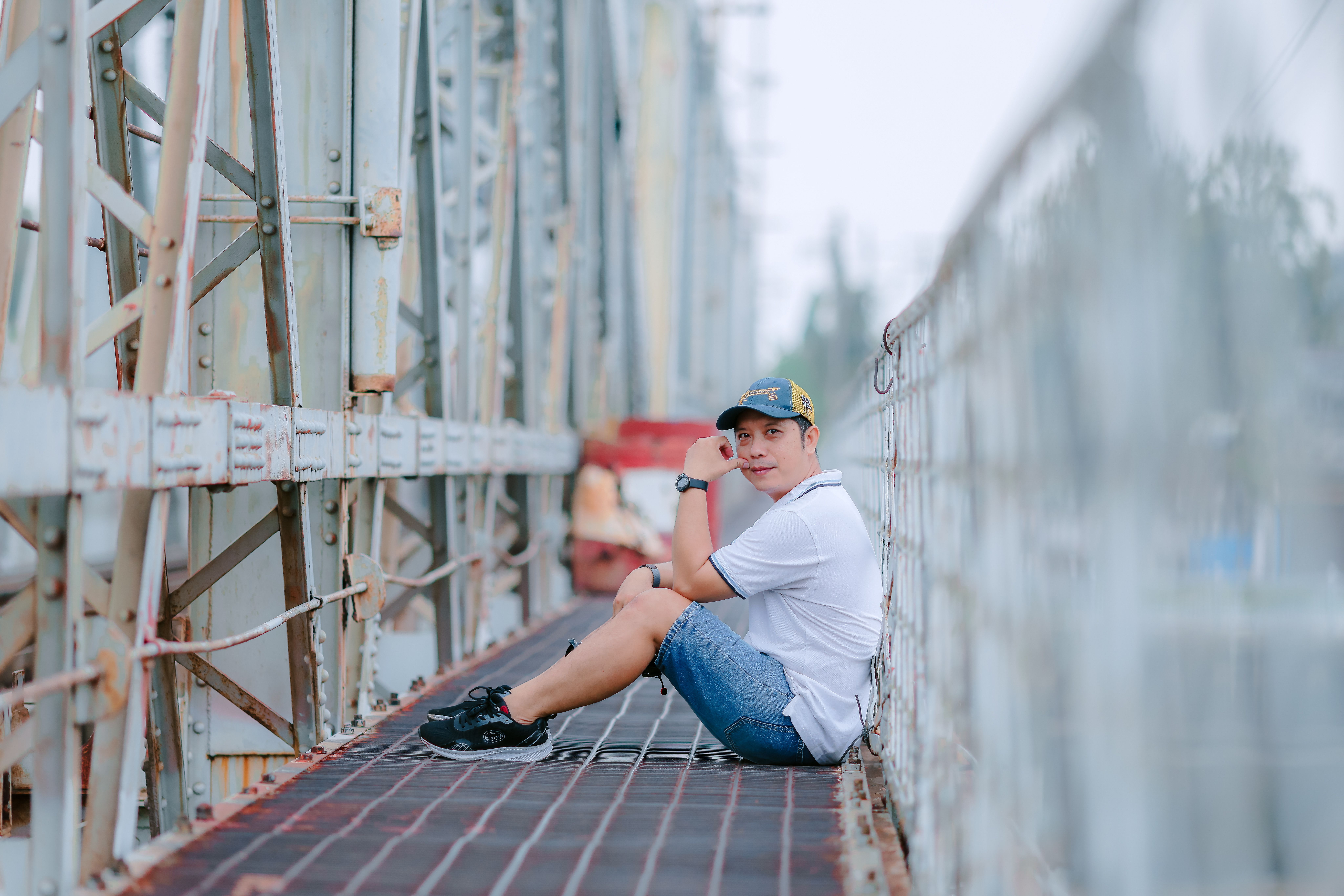 Man Sitting On Industrial Bridge Smiling · Free Stock Photo