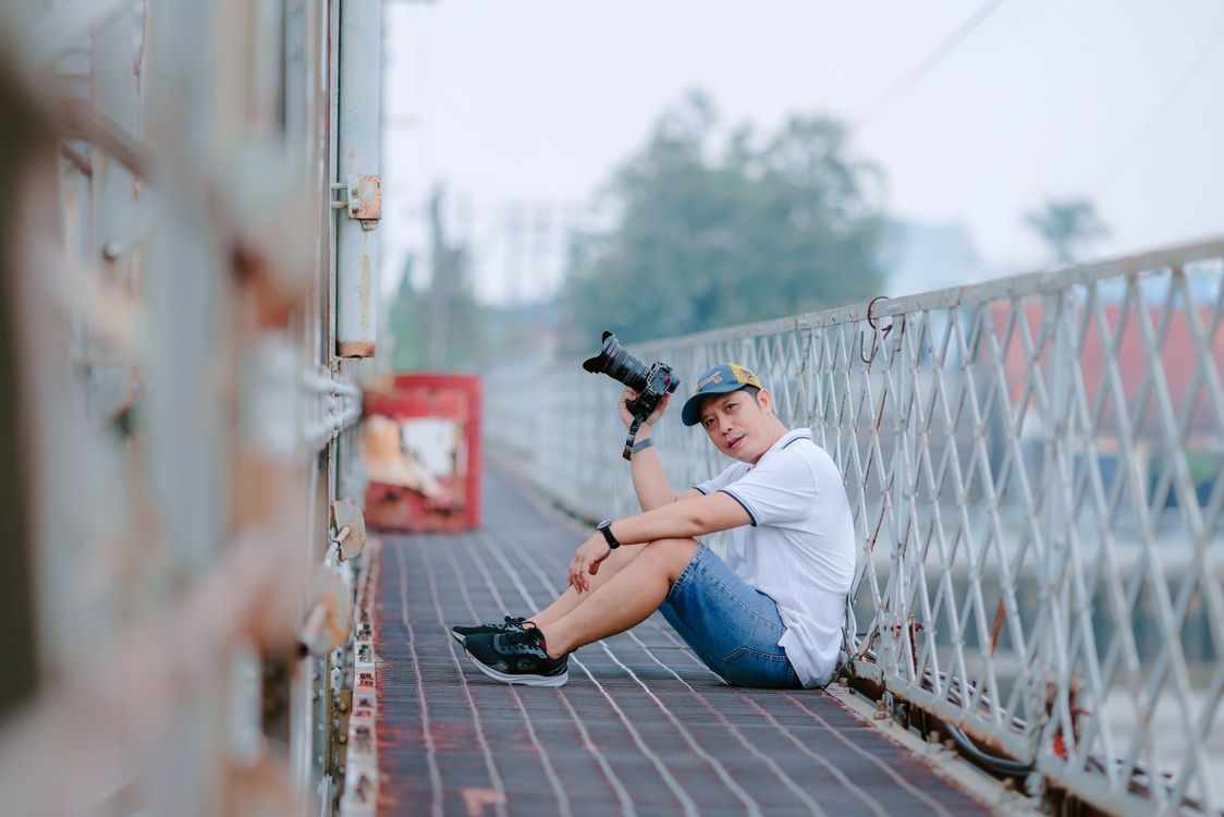 Young Photographer Sitting on Urban Bridge · Free Stock Photo