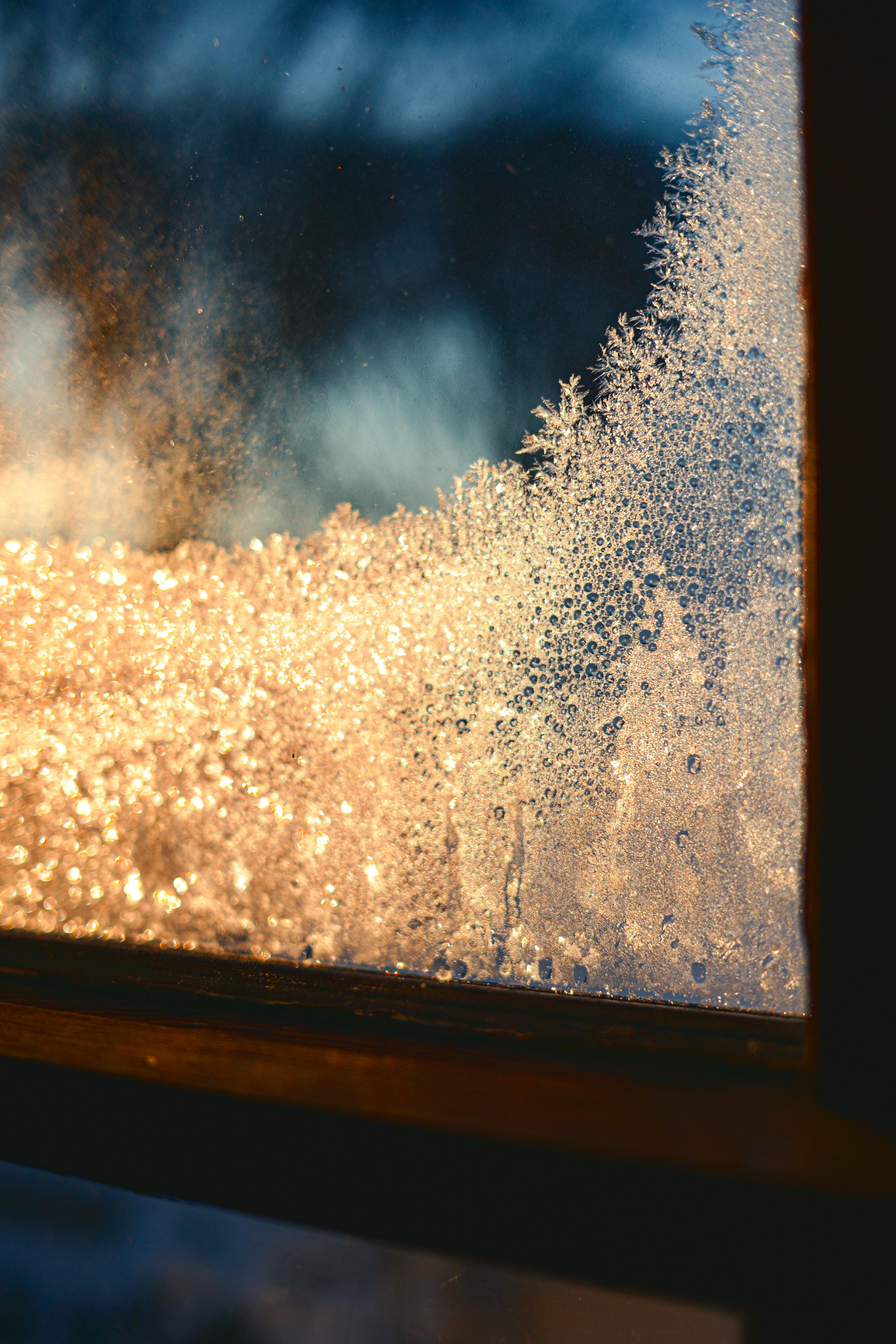 Close-up of a frosted window with golden light at sunrise, creating a warm contrast.
