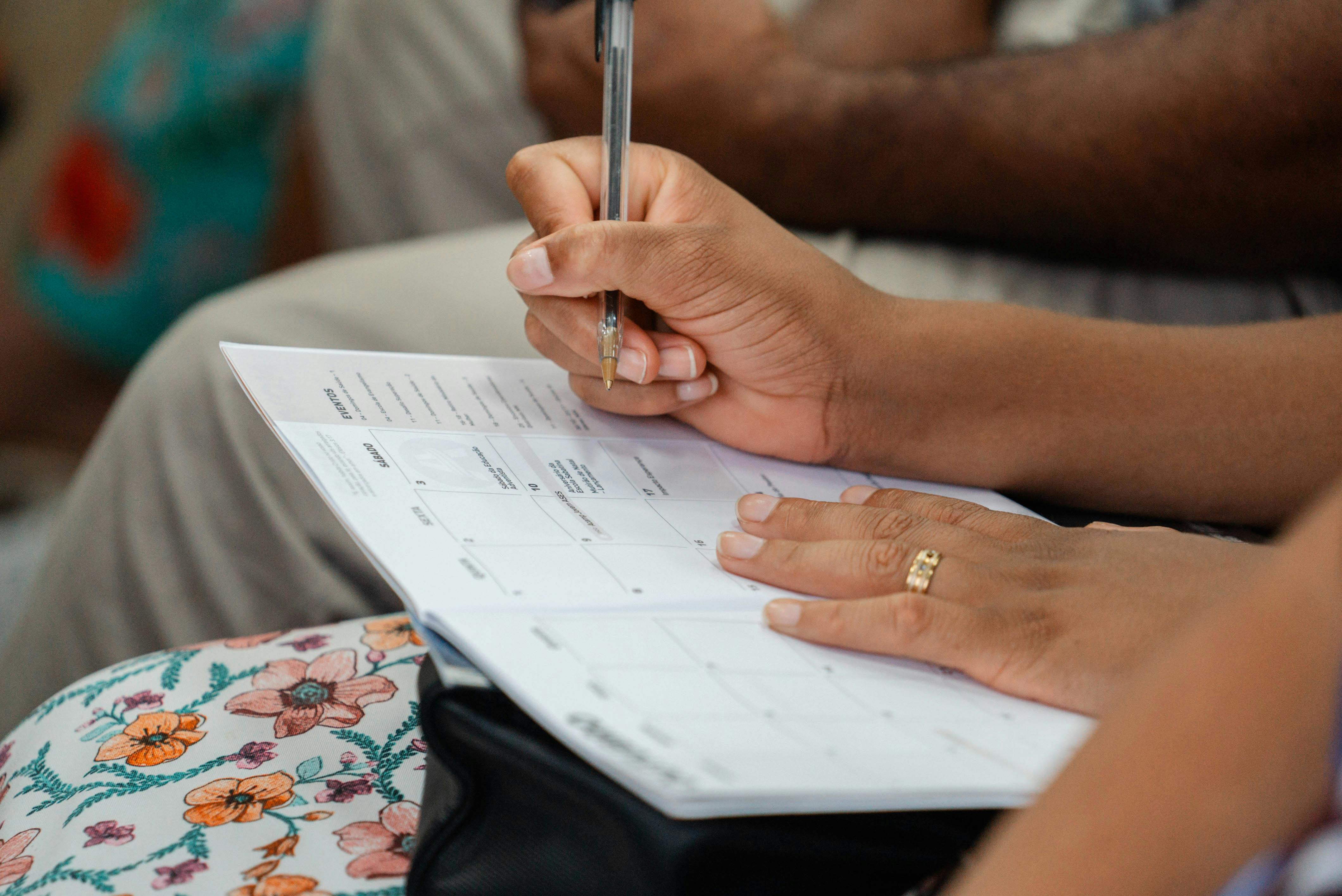 A woman writing in a calendar planner, highlighting organization and time management.