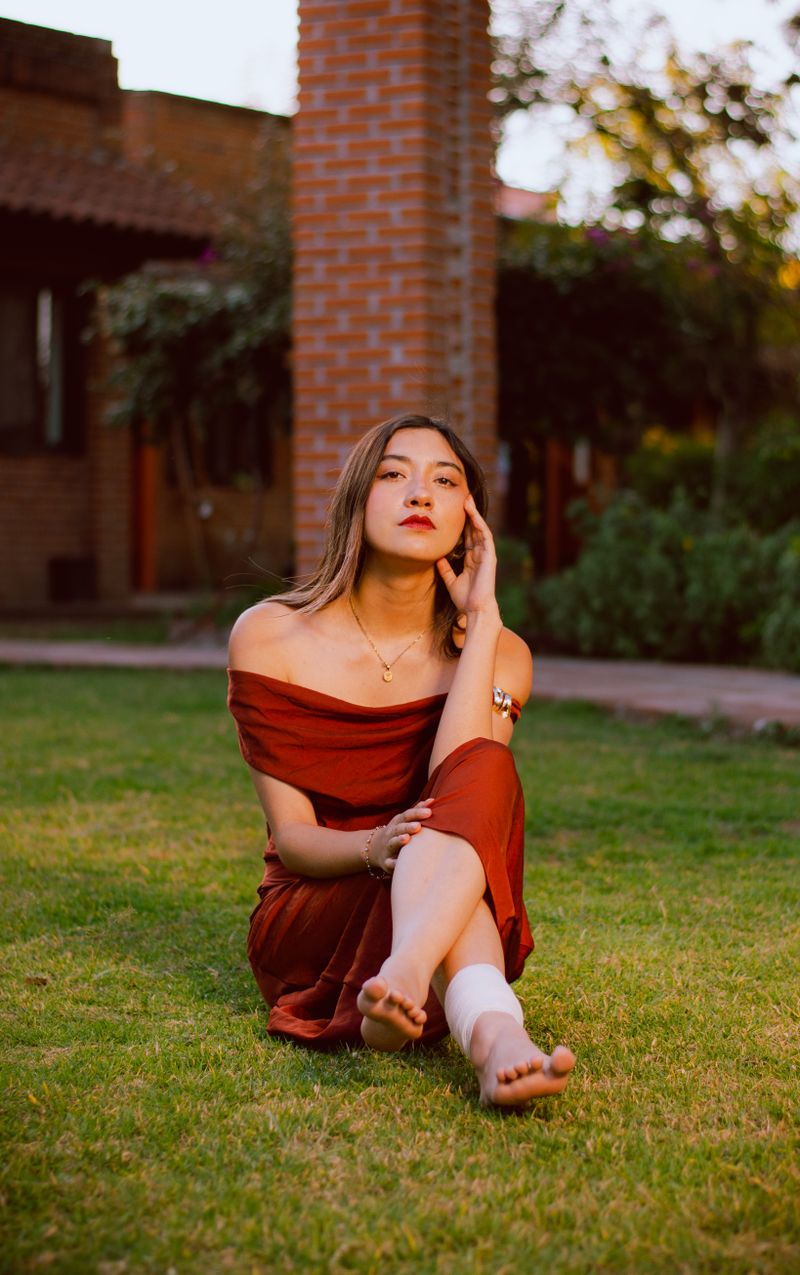 Young Woman in Red Dress Sitting Outdoors · Free Stock Photo