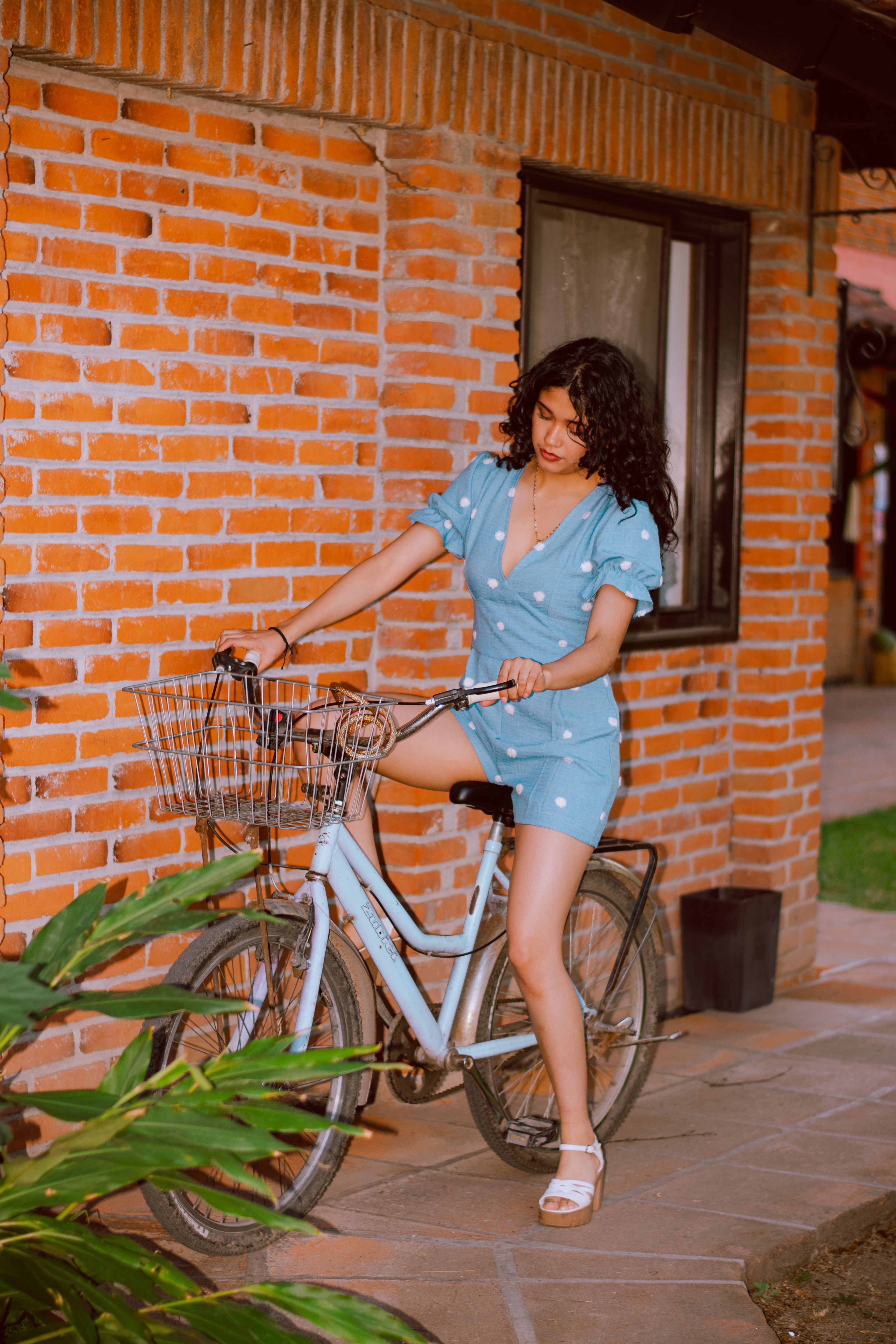 Young Woman in Blue Polka Dot Dress Riding a Bicycle · Free Stock Photo