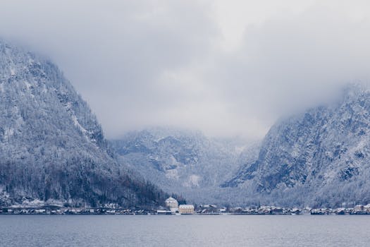 Peaceful snow-covered alpine village nestled between misty winter mountains.