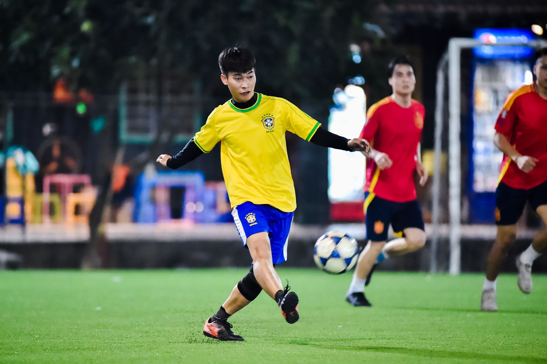 Dynamic soccer match in action at night in Hà Nội, showcasing young athletes playing on a vibrant field.