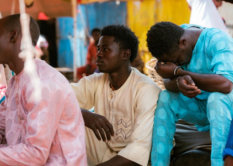 Men gathered in Tudun Wada, Nigeria, wearing traditional attire reflecting Nigerian culture.