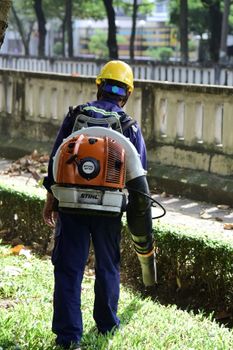 Worker using a leaf blower in a city park