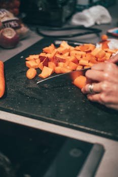 Hands chopping fresh carrots on a cutting board, ideal for cooking and healthy eating themes.