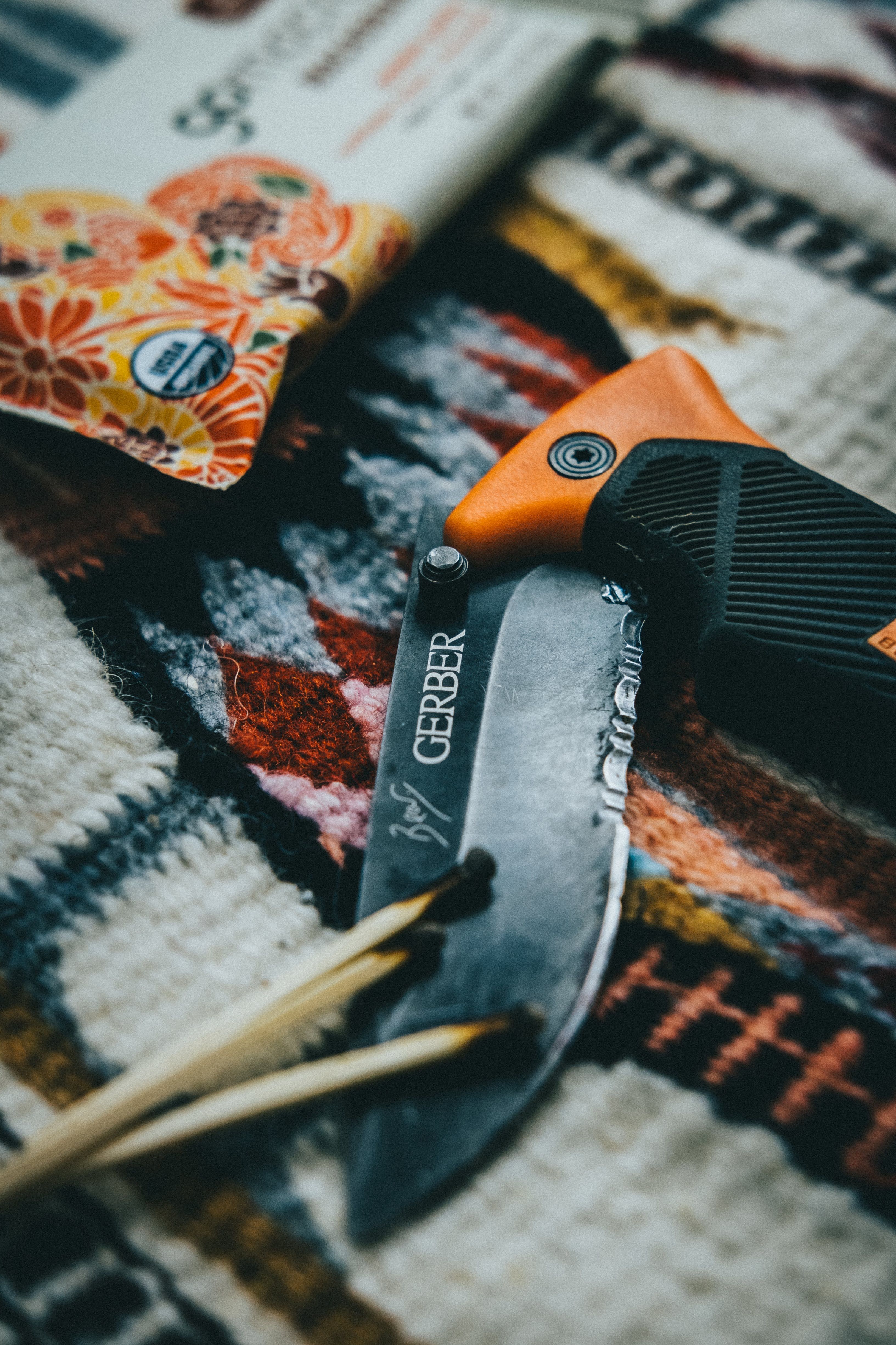 A Gerber folding knife lays on a patterned camping blanket, suggesting adventure and outdoor activities.