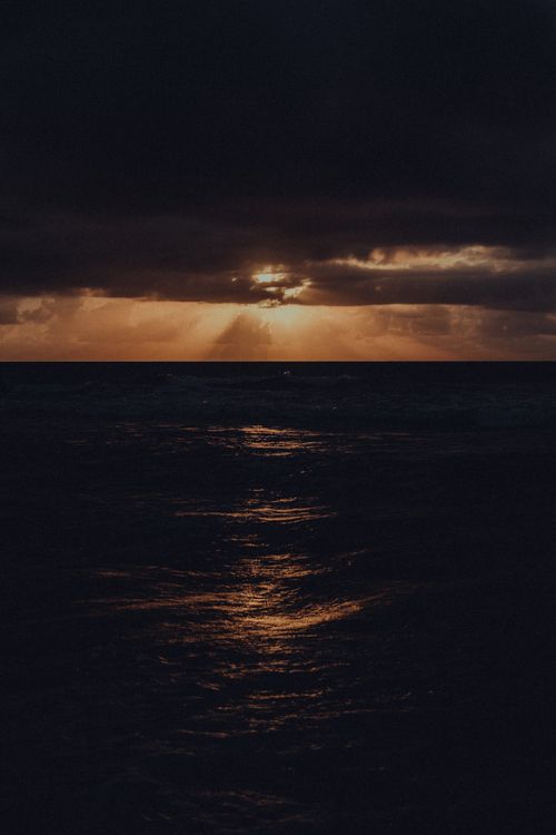 Free A captivating sunset over the ocean with golden reflections on the waves, creating a dramatic and peaceful atmosphere. Stock Photo