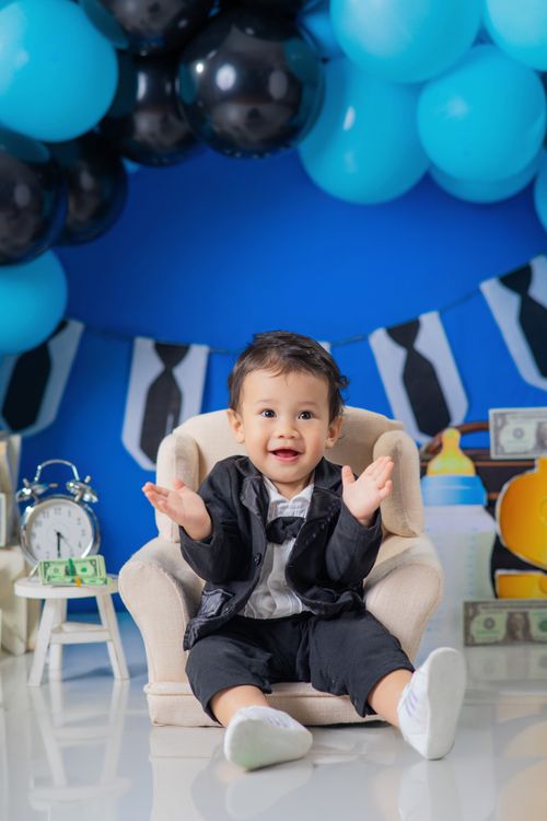 Free Charming baby in suit surrounded by balloons and decor, showcasing a playful business theme. Stock Photo