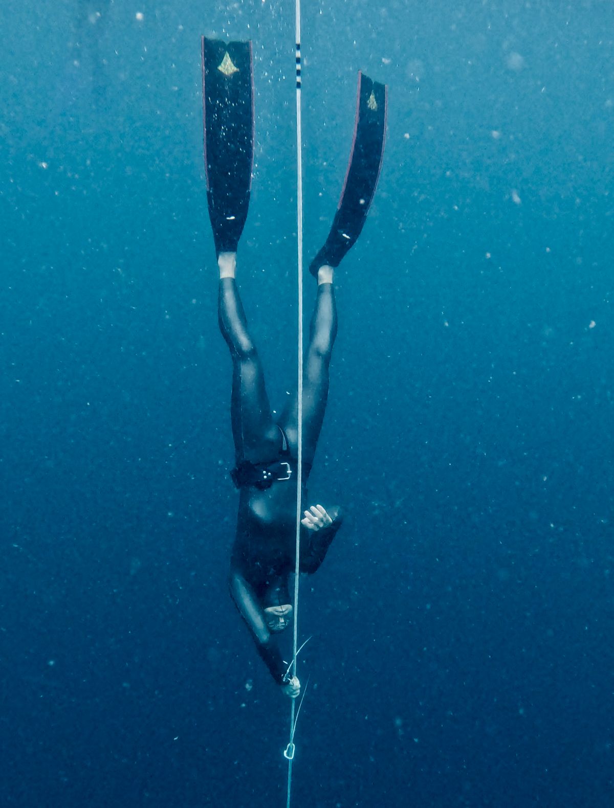 Freediver descending into deep blue ocean water, symbolizing going beneath the surface to the base of the money iceberg