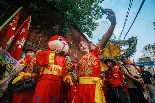 Free Group enjoying a traditional festival with vibrant costumes and a dragon dance, capturing the joyous spirit of the event. Stock Photo