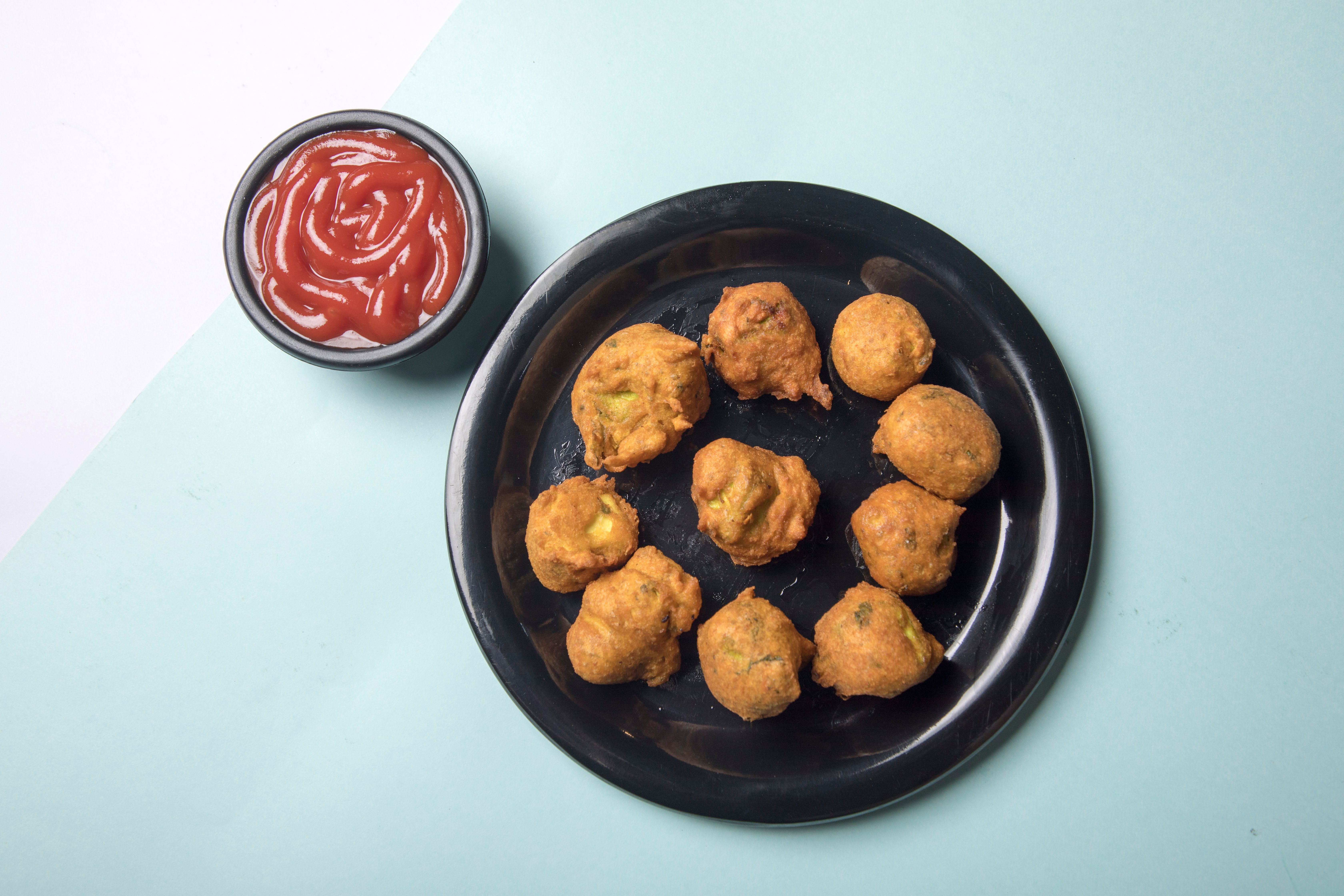 Delicious Indian pakoras served on a plate with ketchup, perfect for snack time.