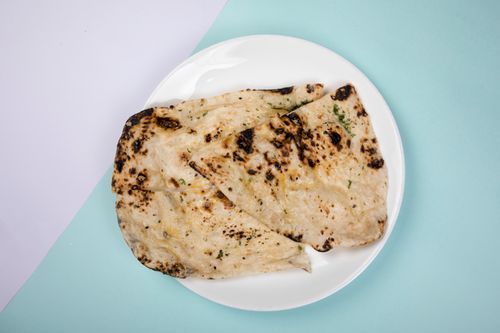 Free Appetizing garlic naan bread served on a white plate against a blue background. Stock Photo