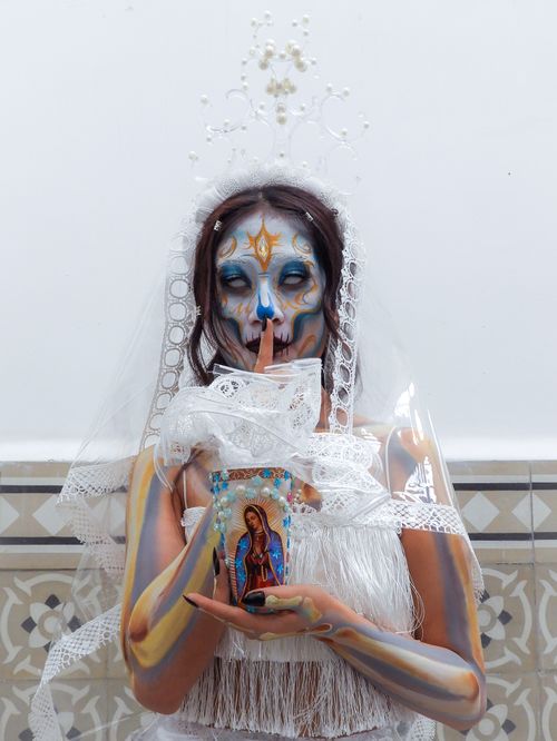 Free Artistic portrait of a woman in Catrina makeup holding a candle, celebrating Dia de los Muertos. Stock Photo