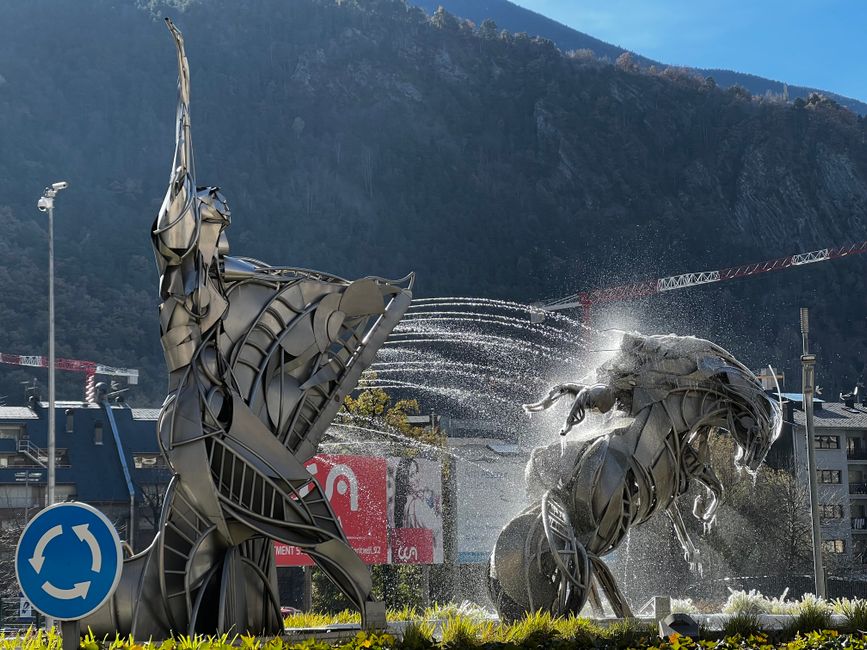 Dynamic metal sculptures with fountains in Andorra's capital city.