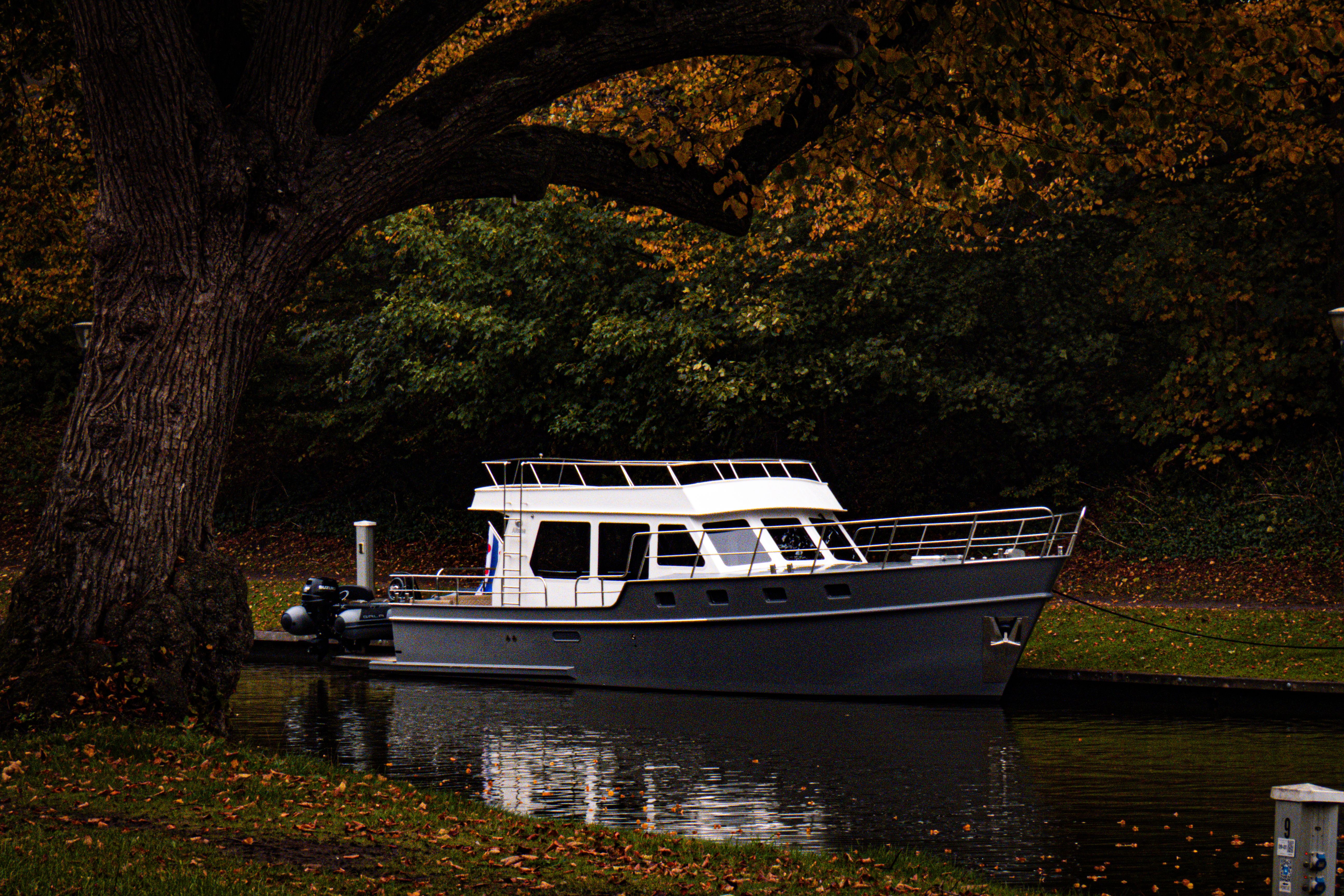 Modern Boat Docked in Autumn Forest Canal