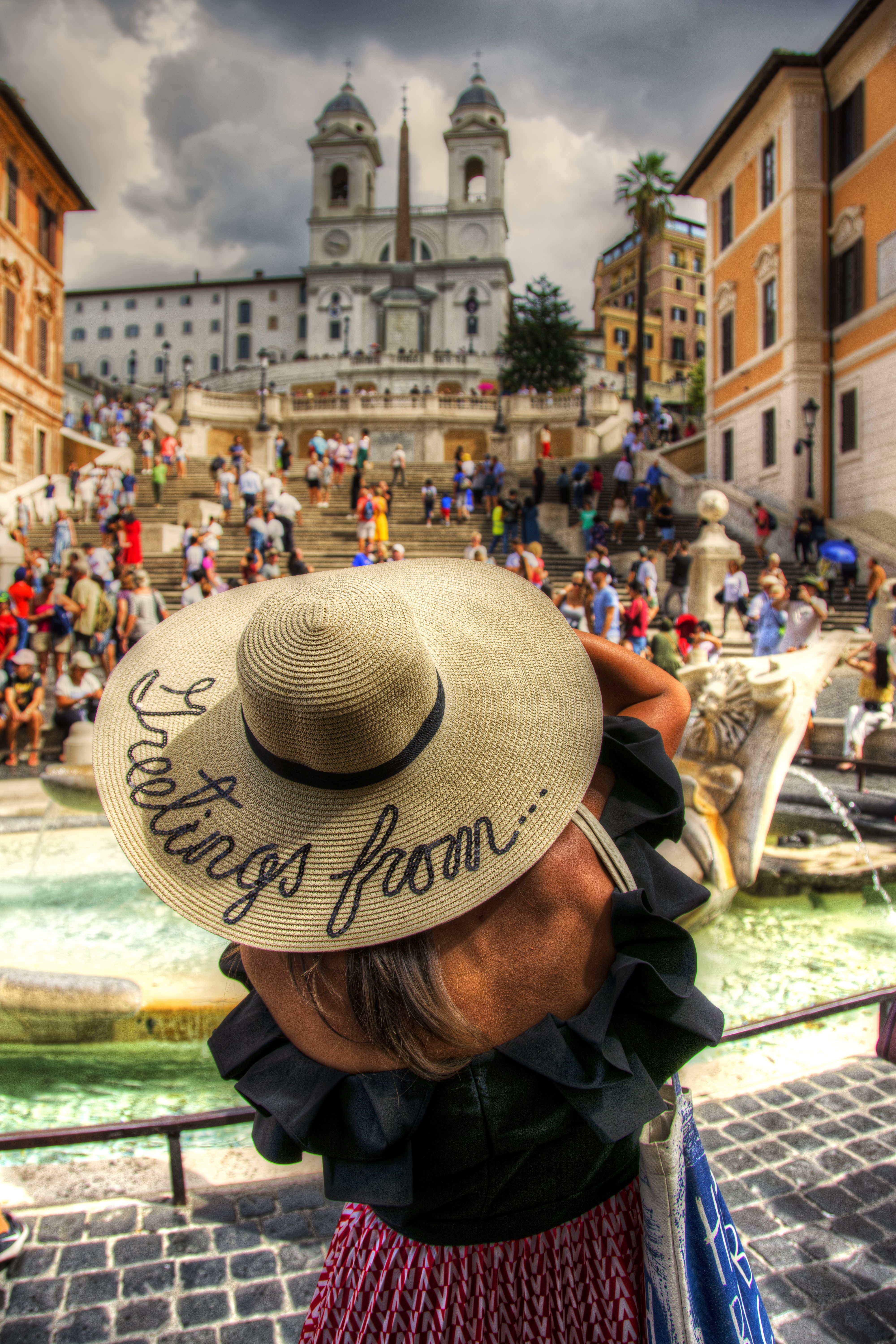 A tourist wearing a wide-brimmed hat enjoys the view of the Spanish Steps in Rome.