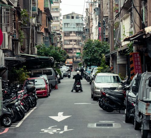 Free Bustling urban street in New Taipei City with scooters and cars showcasing typical Taiwanese urban life. Stock Photo