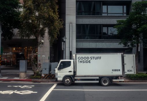 White delivery truck parked on an urban street in Taipei, Taiwan in front of a modern building.