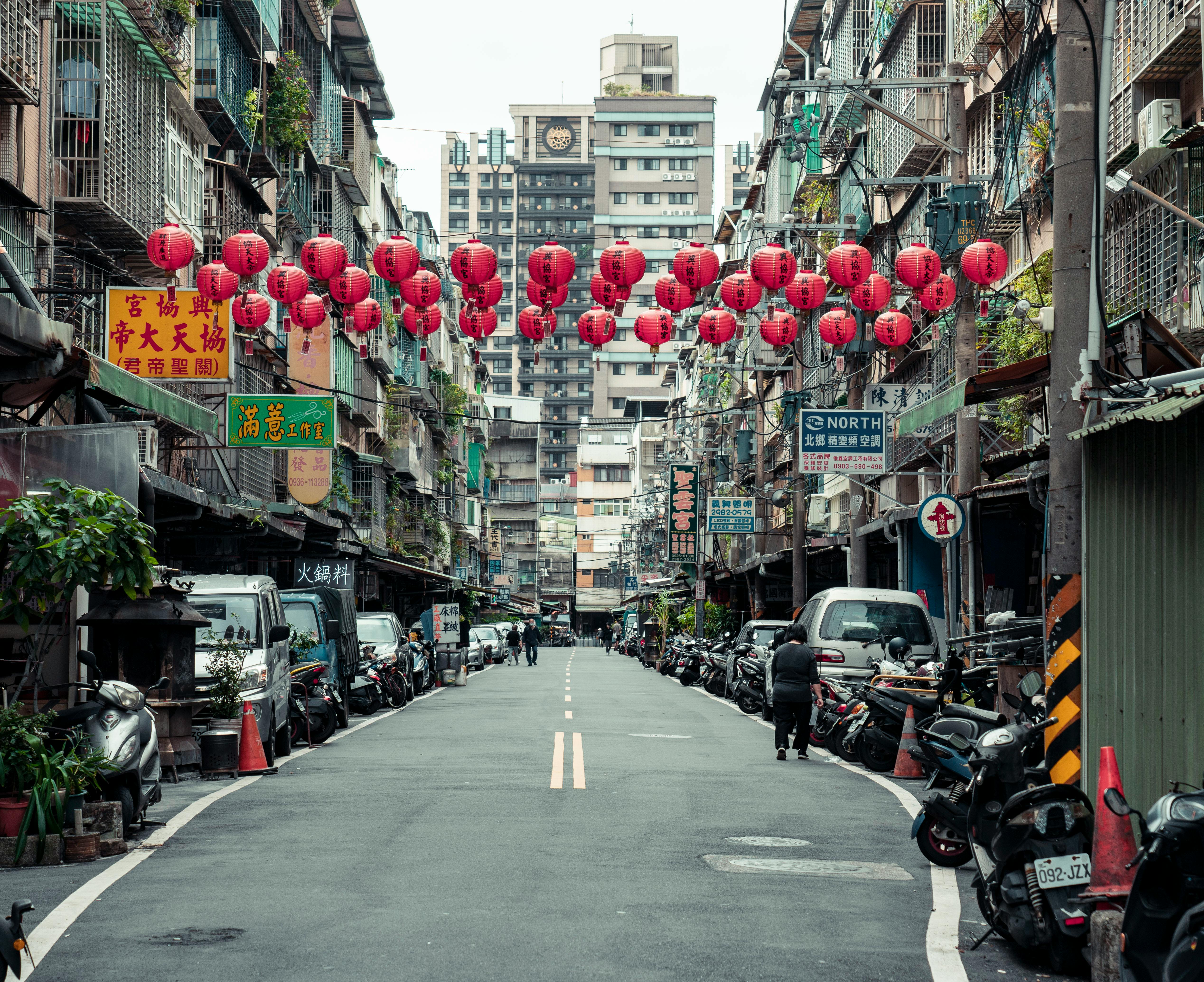 A bustling urban street in New Taipei City adorned with traditional red lanterns, capturing local culture.