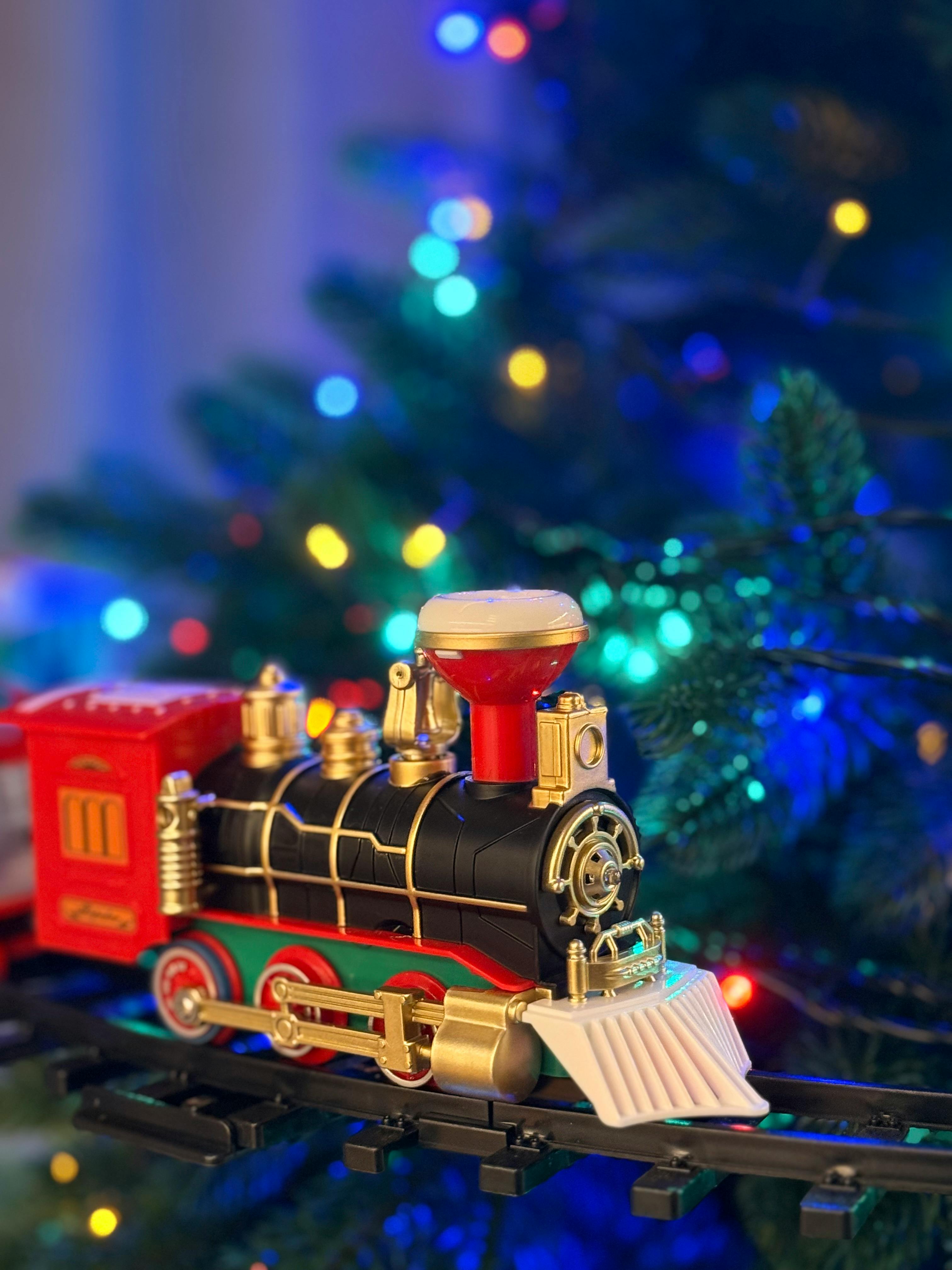 Colorful toy train on a festive Christmas tree track with shimmering lights.