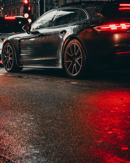 From below of glowing headlights of modern car on asphalt road with red traffic light