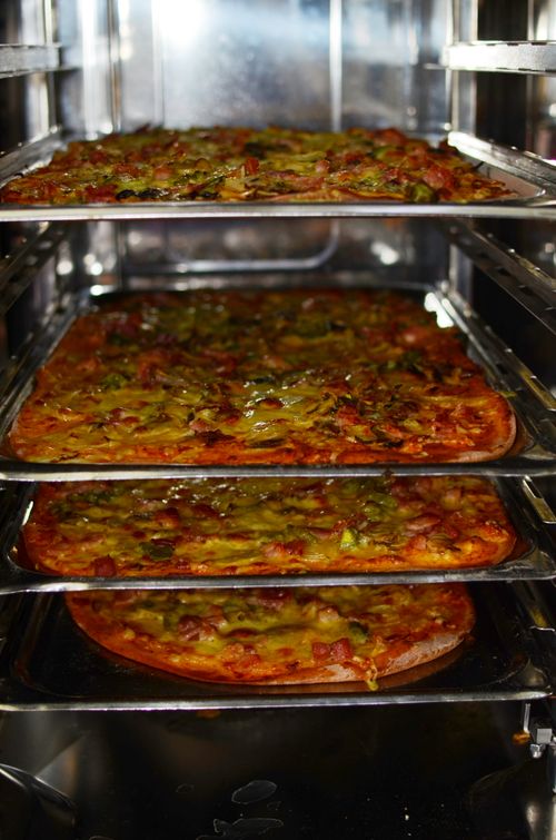 Free Freshly baked pizzas in an industrial oven, topped with green peppers and cheese. Stock Photo