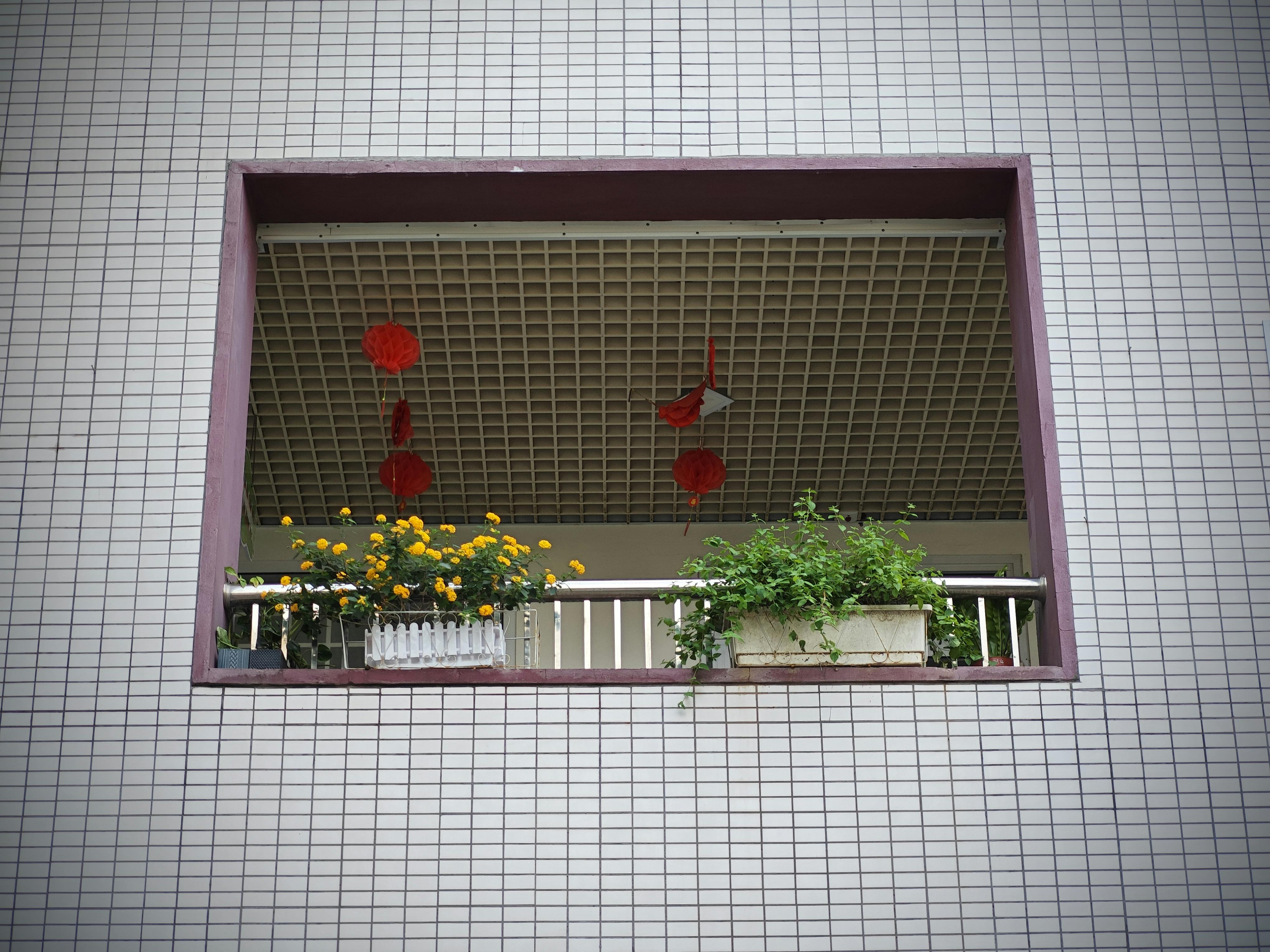 Kostenlos Ein Balkon im Freien mit leuchtenden Blumen und darüber hängenden roten Laternen. Stock-Foto