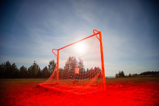 A glowing soccer goal under a bright night sky, creating a surreal outdoor scene.