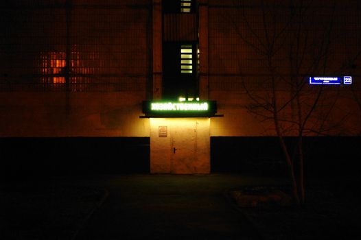 A dark urban scene illuminated by a neon sign, creating a moody atmosphere.
