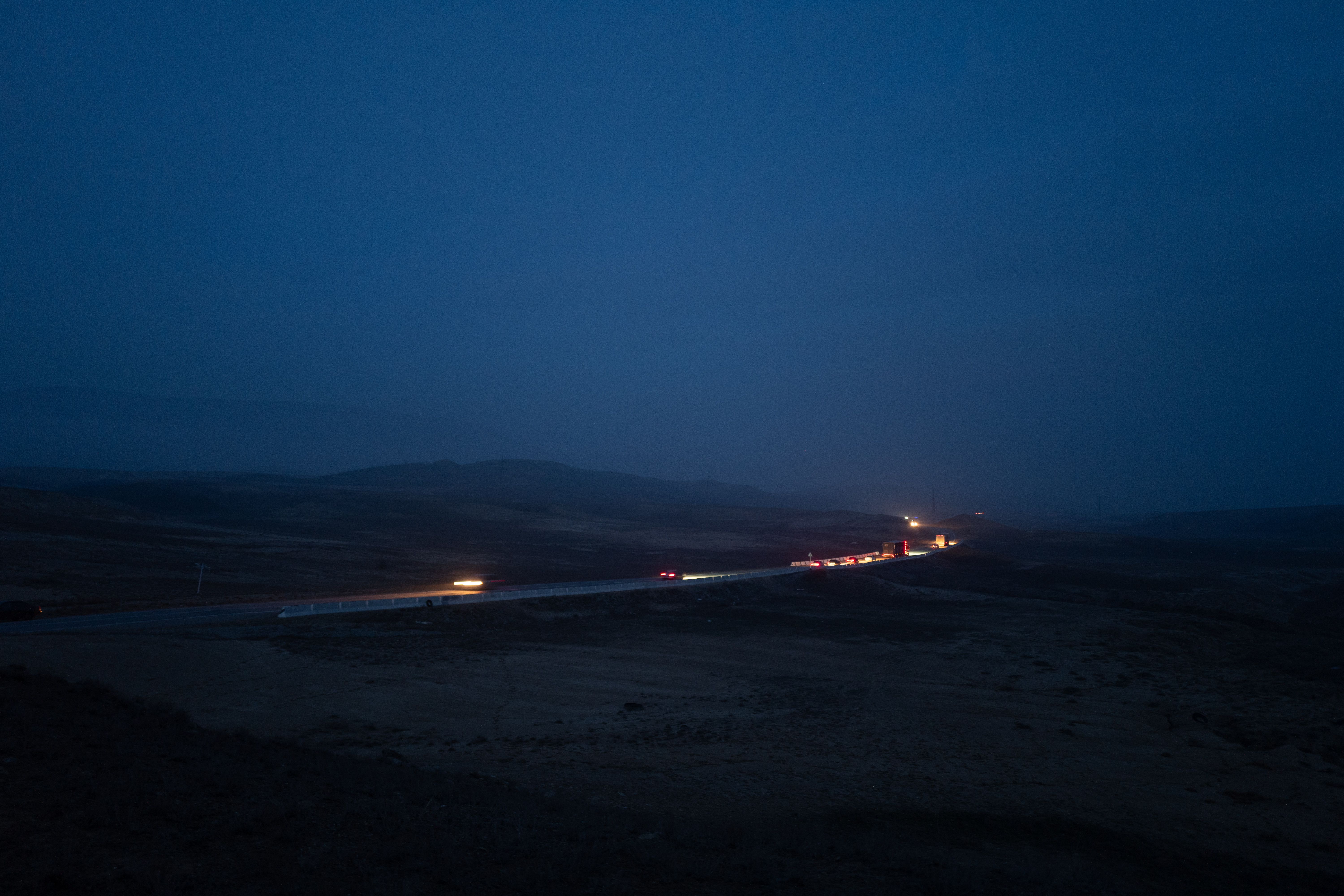 Long exposure of cars on a highway at night with minimal lighting, creating a serene nighttime scene