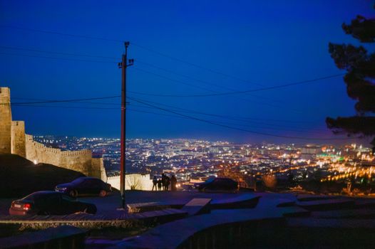 Beautiful night cityscape from a fortress with glowing city lights and a clear sky.