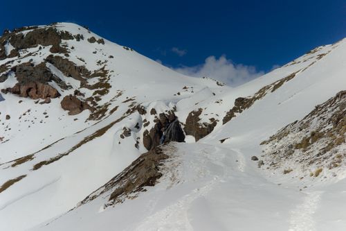 Free Serene snow-covered mountain scene with a small waterfall under a clear blue sky. Stock Photo