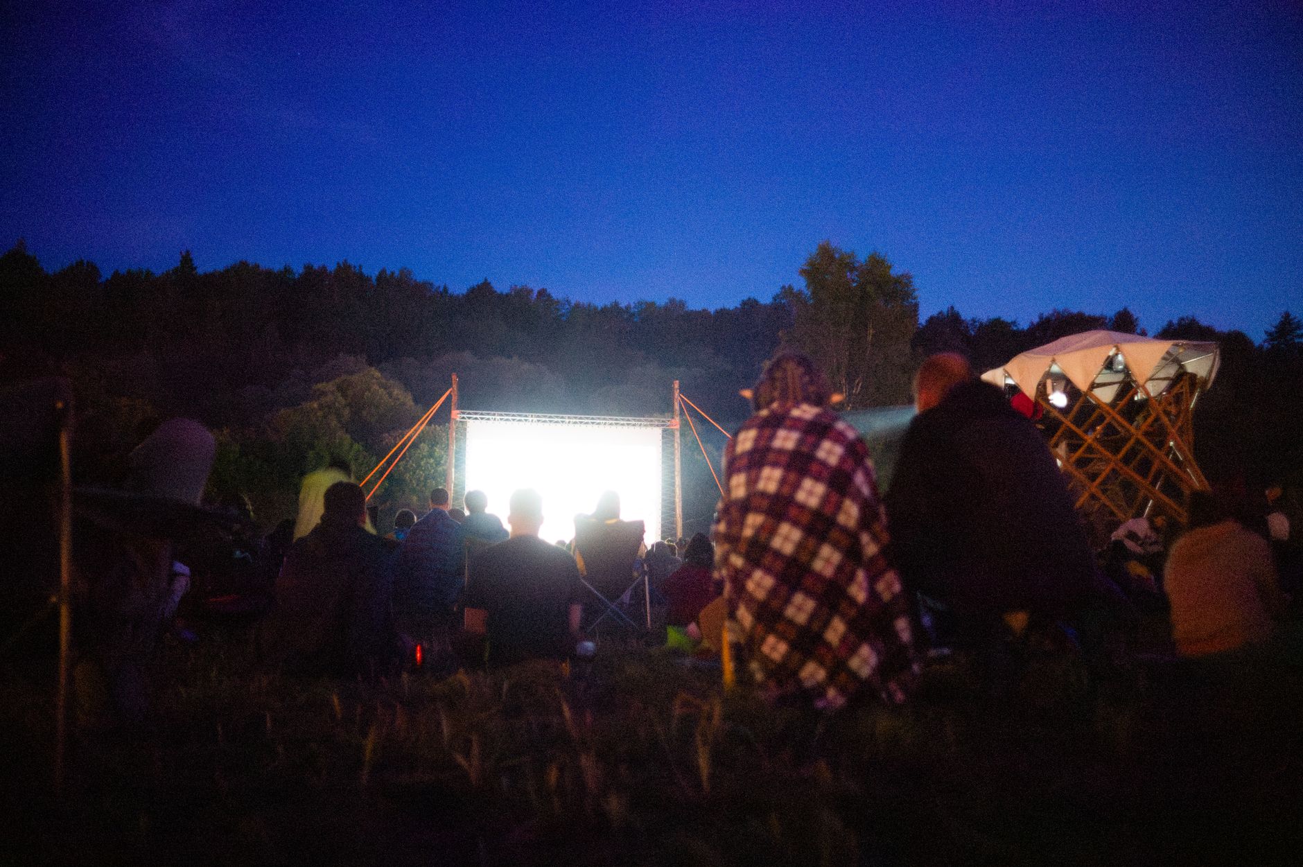 Adults gather outdoors for a night movie screening under the stars.