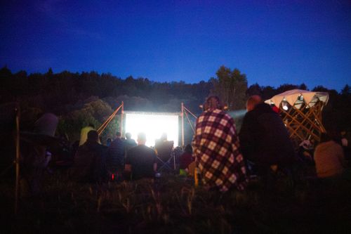 Free Adults gather outdoors for a night movie screening under the stars. Stock Photo