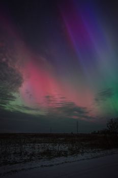 Captivating aurora borealis in vibrant colors over snowy landscape at night.