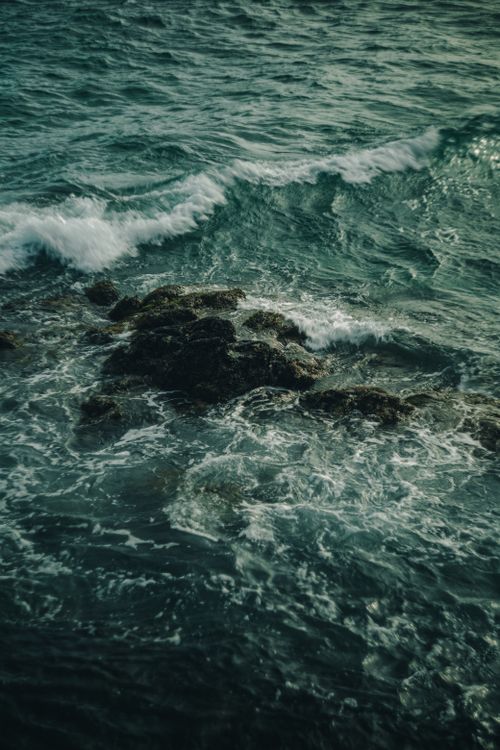Free Serene ocean waves crashing on a rocky shore with foamy water details. Stock Photo